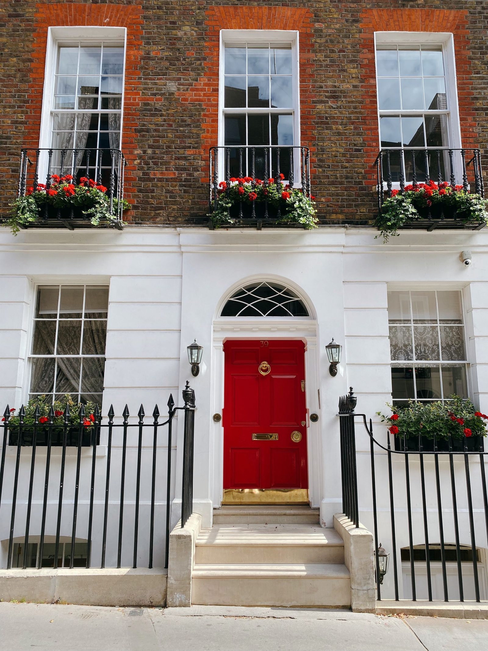 A period townhouse front with tall sash windows and a red door